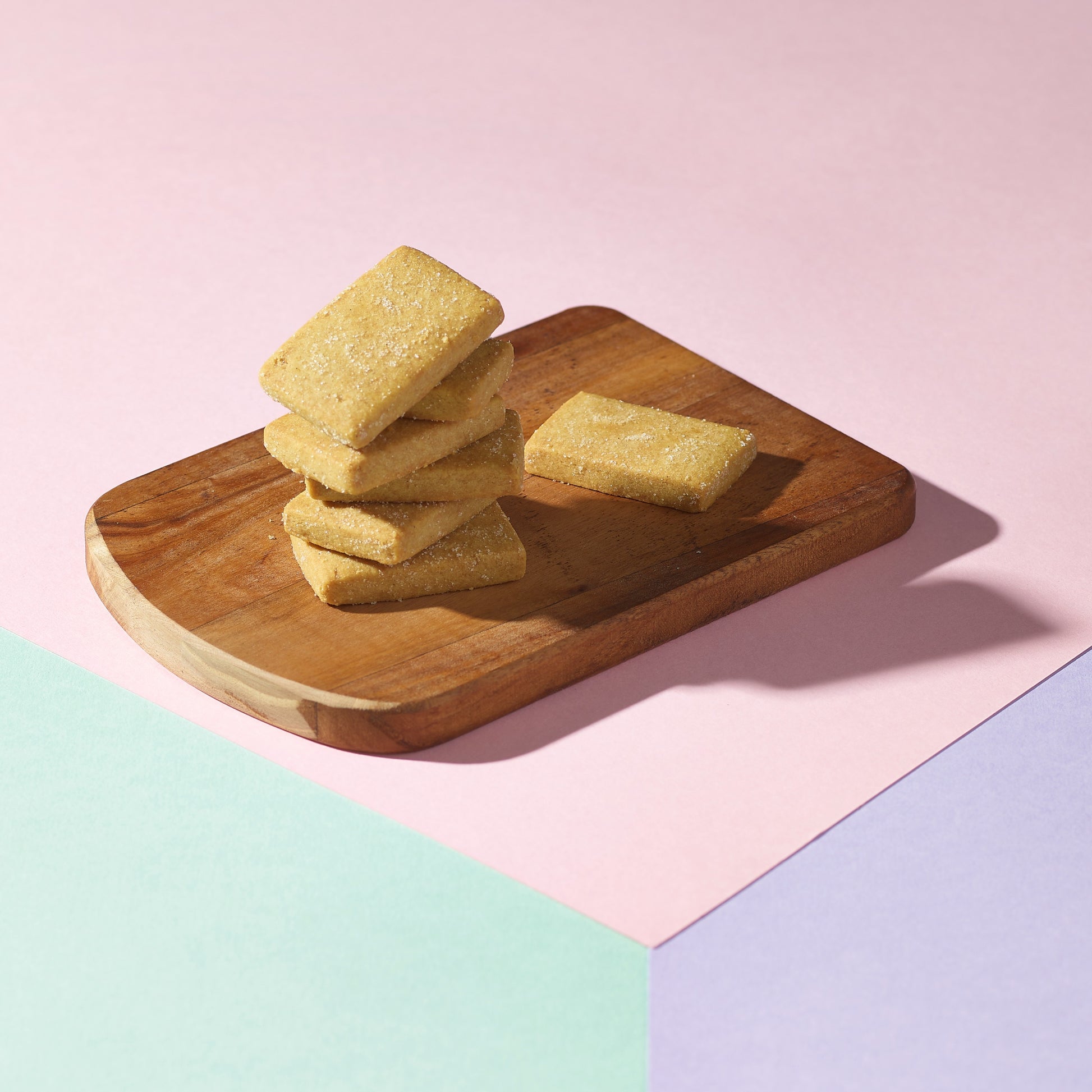 shortbread stacked on wooden board on multicolored background